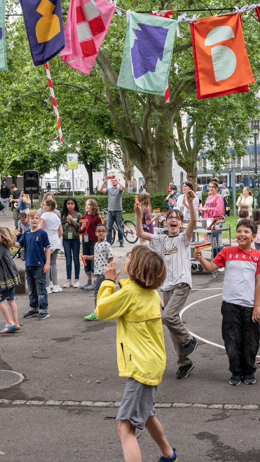 Kinder spielen auf der Strasse unter bunten Wimpeln beim Projektauftakt von Museumjung.