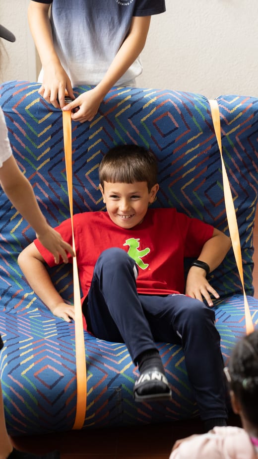 Kinder spielen auf einem grossen selbstgebastelten Stuhl.