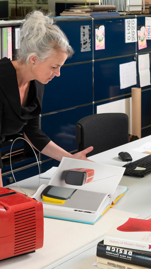 Frau betrachtet Dokumente neben vintage Fernseher im modernen Büro.