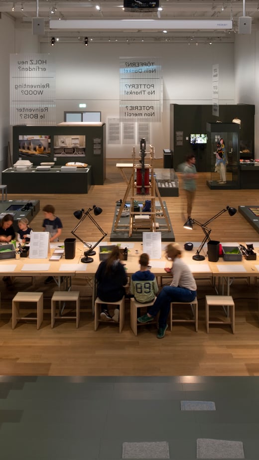 Personen sitzen an einem Tisch in einem modernen Museum.