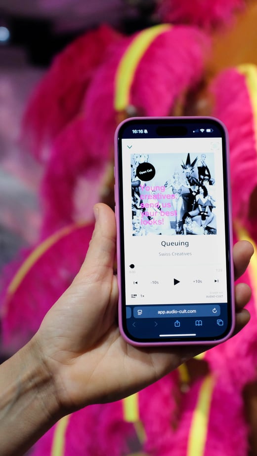 Hand hält Smartphone mit Musik-App vor leuchtend rosa Kostüm.