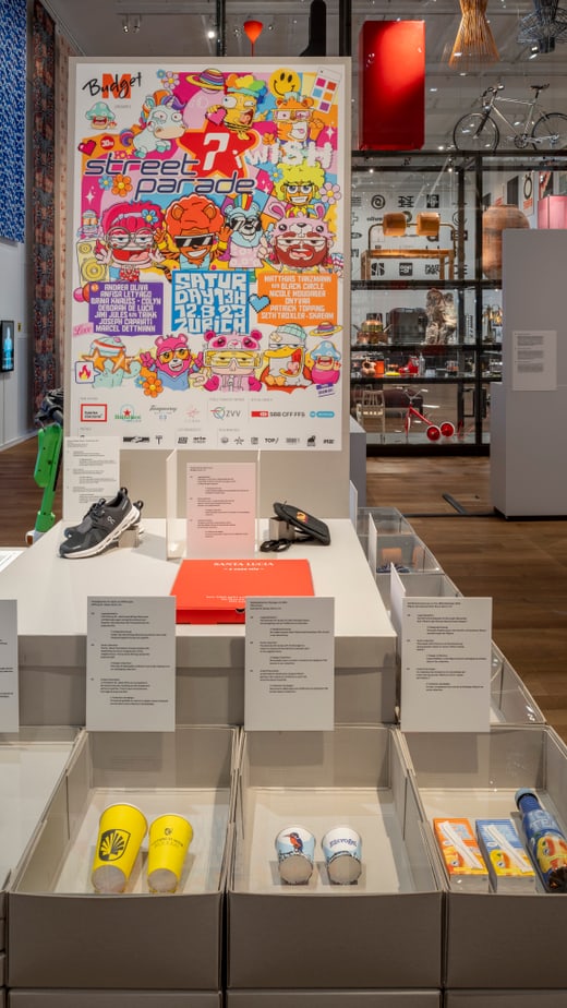 Museumsausstellung mit farbigem Poster und Gegenständen in Vitrinen.