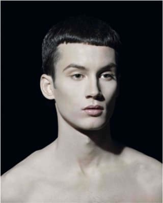 Porträt eines jungen Mannes vor schwarzem Hintergrund.