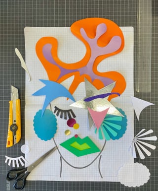 Collage aus buntem Papier auf Rasterpapier mit Bastelwerkzeugen.
