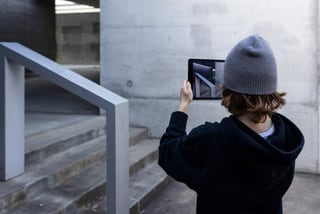 Person fotografiert Treppe mit Tablet in Innenhof.