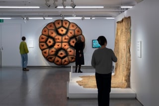 Personen betrachten Ausstellungsstücke in einem modernen Kunstraum.