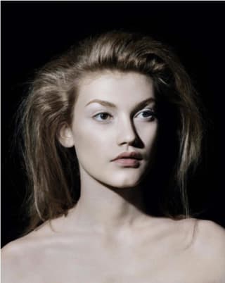 Porträt einer Frau mit langen Haaren vor schwarzem Hintergrund.