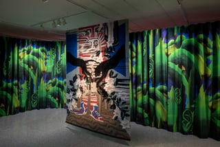 Galerieraum mit bunten Vorhängen und einem zentralen Kunstwerk.