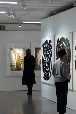 Personen betrachten Kunstwerke in einer Galerie.