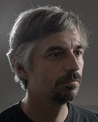 Porträt eines Mannes mit grauen Haaren und Bart.