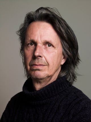 Porträt eines Mannes mit langen Haaren in schwarzem Pullover.