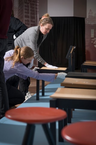 Personen inspizieren Bänke in Ausstellungshalle.