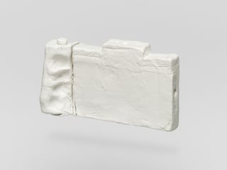 Weisse Skulptur in Form einer Kamera auf grauem Hintergrund.