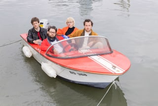 Vier Personen in kleinem Boot auf dem Wasser.