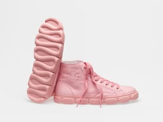 Rosa Turnschuhe mit einem Smiley und gewellter Sohle vor weissem Hintergrund.