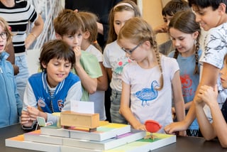 Gruppe von Kindern, die ein Tischspiel betrachten.