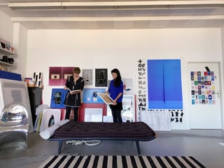 Zwei Personen in einem Kunststudio mit Kunstwerken an den Wänden.