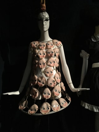Kleid mit Puppenköpfen verziert auf einer Schaufensterpuppe.