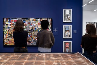 Drei Personen betrachten Kunstwerke in einer Galerie.