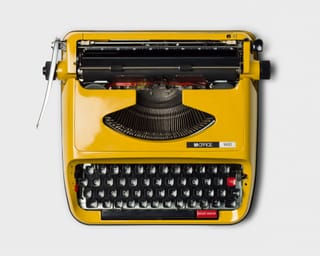 Gelbe Schreibmaschine auf weissem Hintergrund.