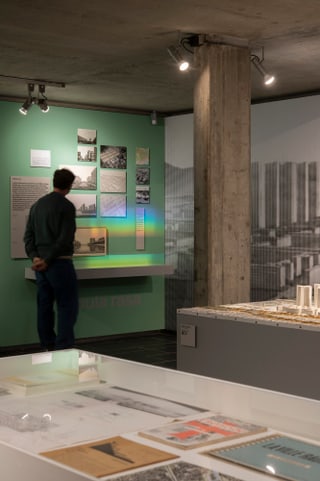 Mann betrachtet Ausstellung in einem Museum mit Fotos und Texten an der Wand.