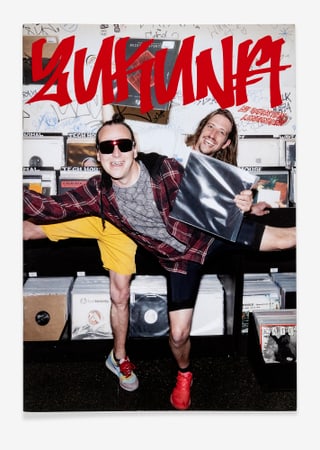 Zwei Personen posieren in einem Musikladen, rote Schrift 'Zukunft'.