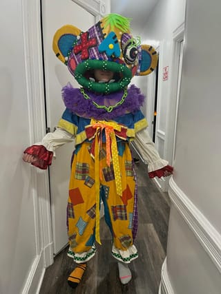 Person in buntem, kreativem Kostüm mit grossem Kopf.