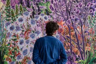 Person betrachtet bunte florale Wandkunst.