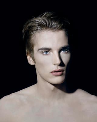 Porträt eines Mannes vor dunklem Hintergrund, leicht angewinkelt nach links schauend.