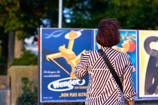 Person vor Plakatwand im Freien stehend.