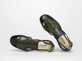 Grüne Sandalen mit Krokodilmuster auf weissem Hintergrund.