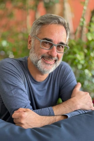 Mann mit Brille und Bart im Freien lächelnd.