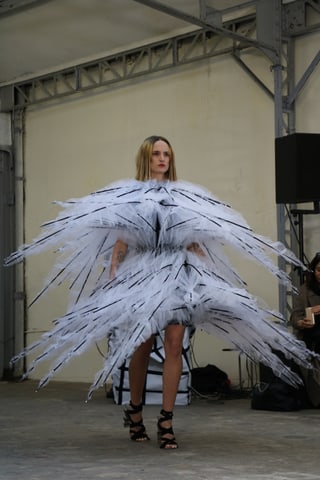 Model in avantgardistischer, federartiger weisser Kleid-Kreation auf Laufsteg.