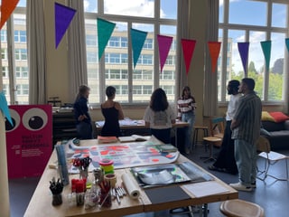 Leute in einem kreativen Workshop-Raum mit Fenstern und Dekorationen.