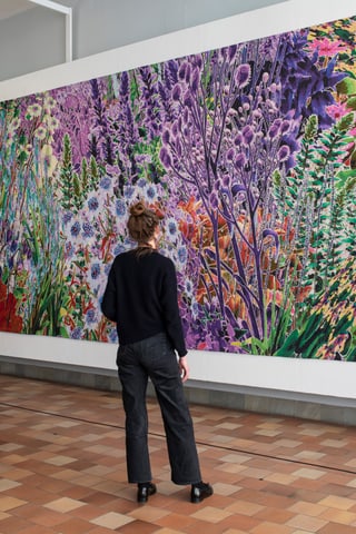 Person betrachtet grossformatiges Gemälde mit Blumenmotiv in Galerie.