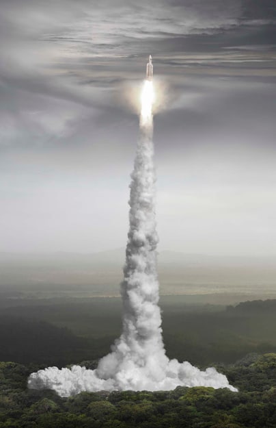 Raketenstart über Landschaft mit Rauchspur.