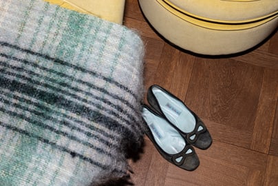 Schuhe neben Decke auf Holzboden neben gelbem Möbelstück.