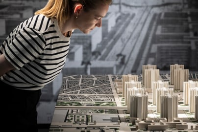 Frau betrachtet architektonisches Modell einer Stadtlandschaft.