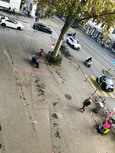 Strassenszene mit Bäumen, Autos und Radfahrer.