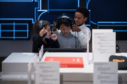 Drei Kinder hören mit Kopfhörern im Ausstellungsraum Musik.