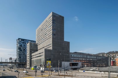 Moderner Bürogebäudekomplex mit Strassenszene und blauem Himmel.