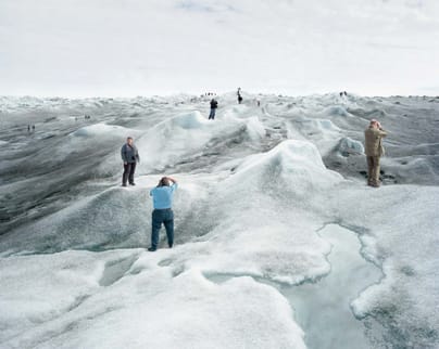 Menschen wandern auf einer weiten Gletscherlandschaft.