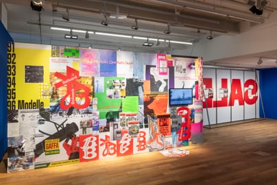 Galeriewand mit bunten Postern und Grafiken ausgestellt.