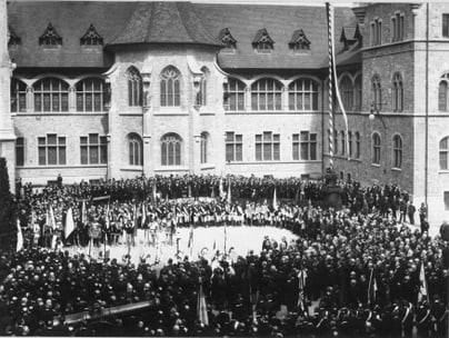 Menschenmenge bei einer Zeremonie vor einem historischen Gebäude.