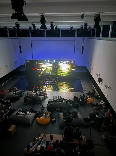 Menschen schauen in dunklem Raum einen Film auf grosser Leinwand an.