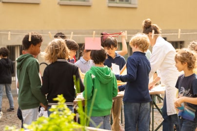 Kinder, die bei einer Kunst- und Handwerksaktivität im Freien mitmachen.