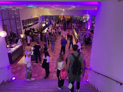 Menschen in einer beleuchteten Lobby von oben gesehen.