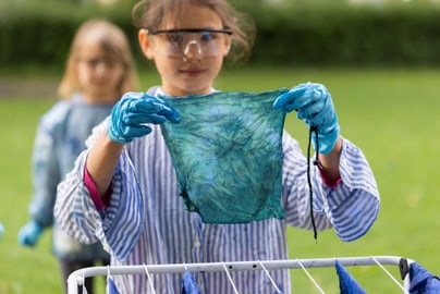 Kind hält gefärbtes Tuch mit Handschuhen.