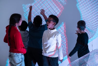 Kinder tanzen vor farbigen Lichtprojektionen.