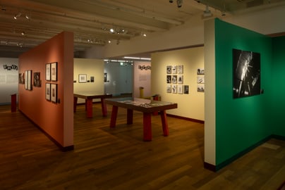 Ausstellungsraum mit Fotos an bunten Wänden.